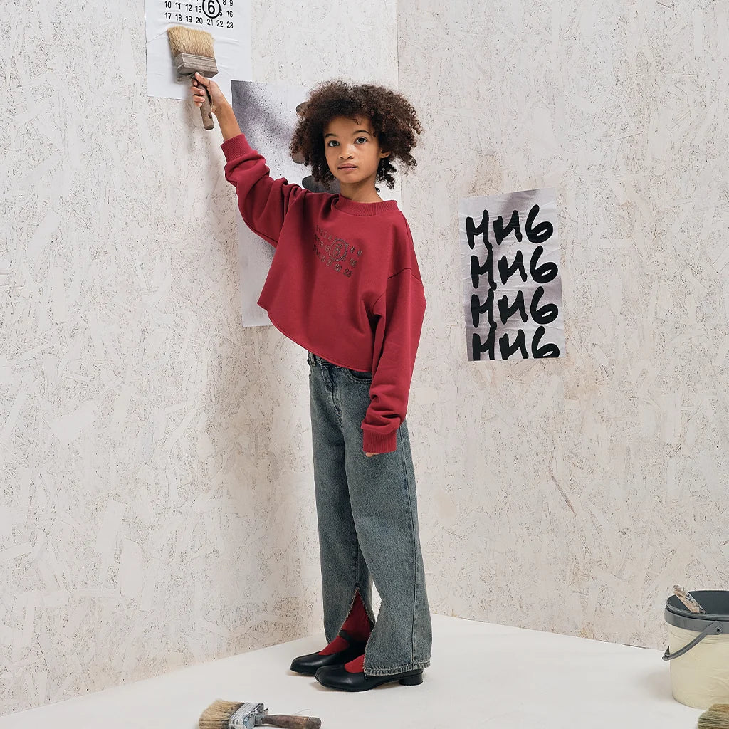 A girl painting the wall while wearing a stylish outfit designed by MM6 Maison Margiela
