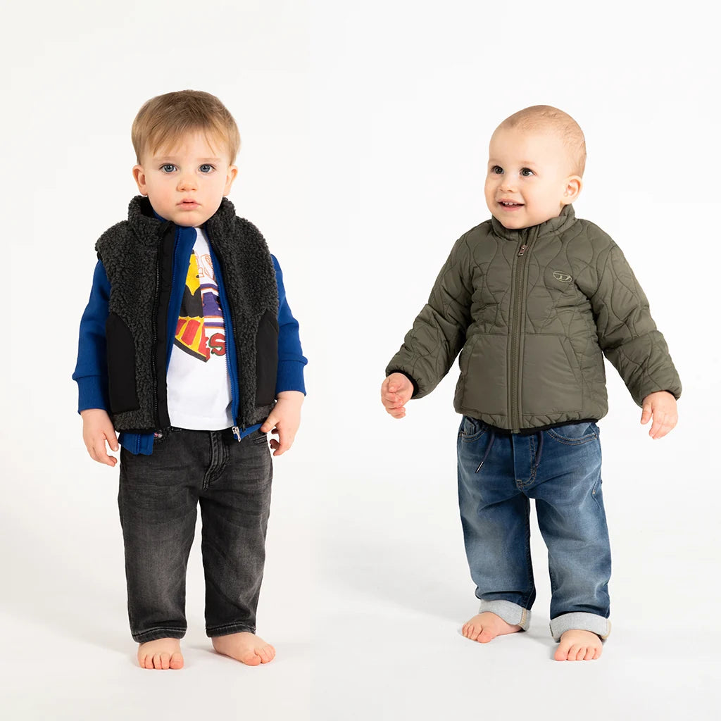 Two babies posing with stylish and warm outfits on a neutral background.