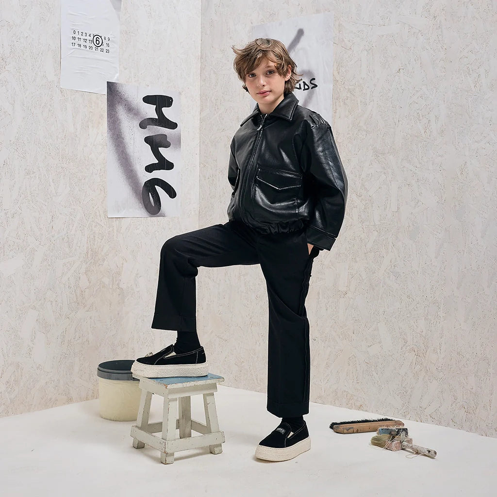 A boy in a painted room, posing in a black outfit